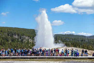 Tourists watching Old Faithful erupting